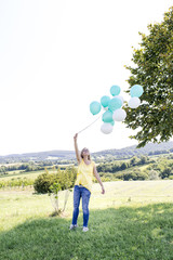 Happy Woman with balloons standing on the meadow