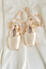 Ballet pointe shoes on beige color fabric background