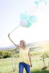 Happy Woman with balloons standing on the meadow