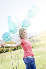Happy Woman with balloons standing on the meadow