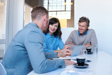 Smiling coworkers using a digital tablet together in an office