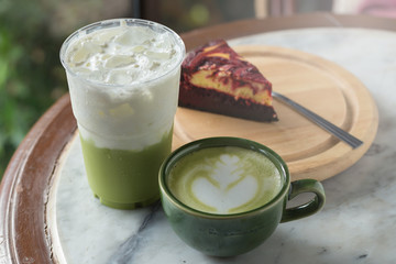 Green tea frappucino in takeaway cup and cheesecake on the marble background
