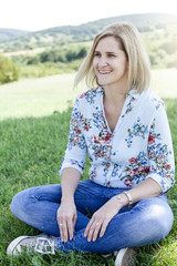 Happy satisfied Woman sitting in the meadow
