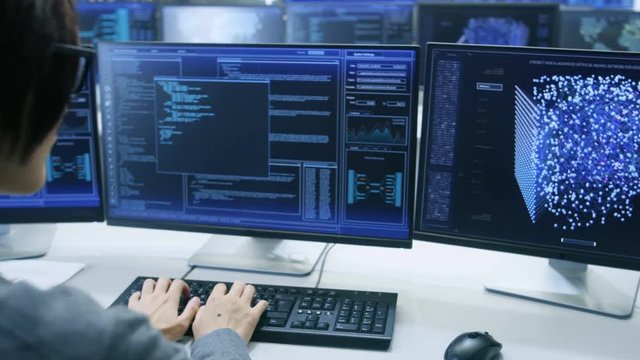 Technical Controller/ Operator Working at His Workstation with Multiple Displays Showing Graphics. Possible Power Plant/ Airport Dispatcher/ Dam Worker/ Data Center/ Government Surveillance.