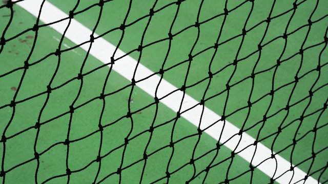 black tennis net on a green cement court