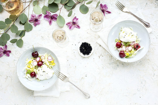 Cherry Burrata Salad served with a Lemon Vinaigrette and Ros&eacute; Wine.  Photographed on a off white/white plaster background.