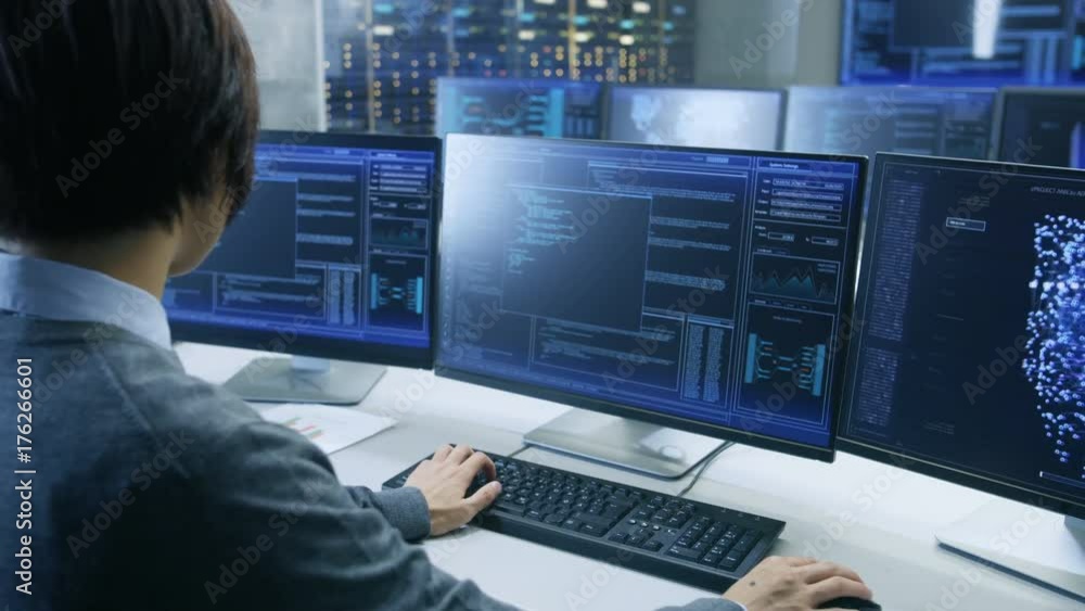 Poster In the System Control Room Technical Operator Works at His Workstation with Multiple Displays Showing Graphics. Possible Power Plant/ Airport Dispatcher/ Data Center/ Government Surveillance/ Space.