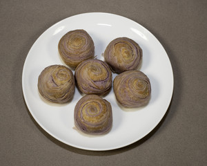 Taiwanese taro mooncakes on a white plate against a light brown background.  Mooncakes are popular for the Asian Mid-Autumn Moon Festival.