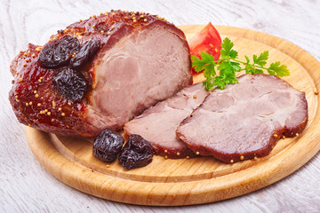 Pork stew with prunes on wooden plate on white background