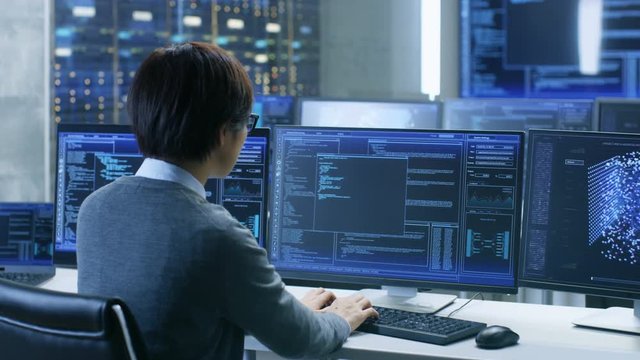 In the System Control Room Technical Operator Works at His Workstation with Multiple Displays Showing Graphics. IT Technician Works on Artificial Intelligence, Big Data Mining, Neural Network Project.