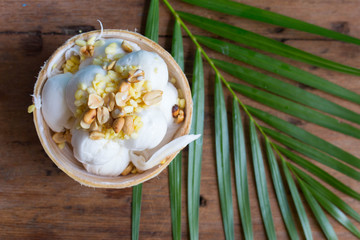 Top view of Coconut Milk Ice Cream in the coconut shell on rustic wooden table. Thai dessert concept.