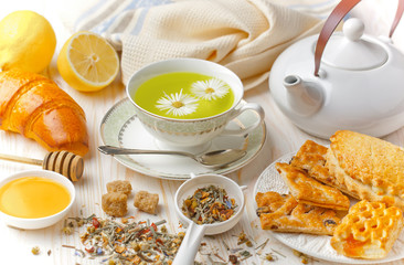 Green tea in a cup on a background of dry leaves of floral tea in a composition with accessories on a white background