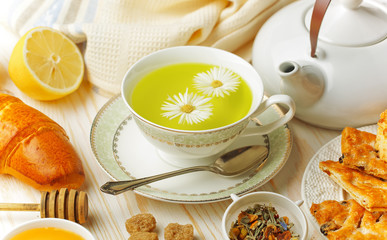 Green tea in a cup on a background of dry leaves of floral tea in a composition with accessories on a white background