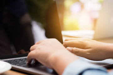 Hands typing on laptop in coffee shop