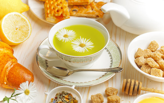 Green tea in a cup on a background of dry leaves of floral tea in a composition with accessories on a white background