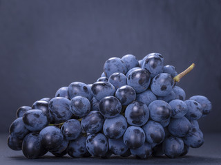 Single branch blue grapes on black slate stone background