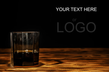 Old scratched glass of scotch whiskey on a wooden table. With place for your text.