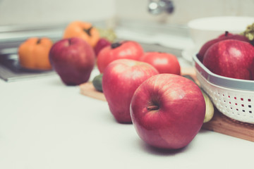Red apples are placed on the table in the kitchen.