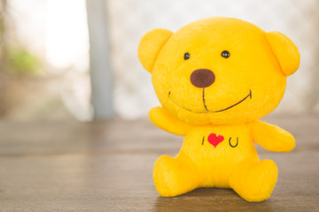yellow teddy bear sitting on wood floor with blur background and vintage tone