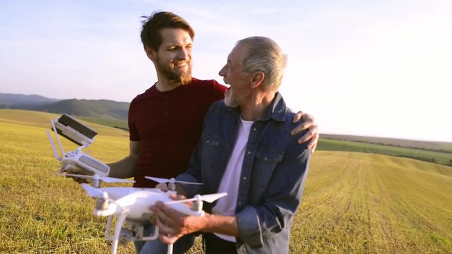 Senior father and his son with drone outdoors.