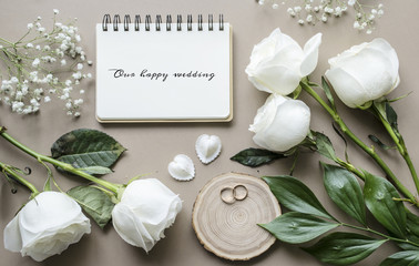 Romantic mockup with flowers and a notebook on a beige background. Roses and a notebook with space for text. Wedding concept. View from above.