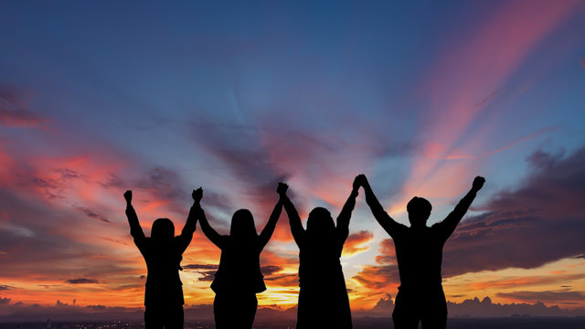 Silhouette of happy business team making high hands in sunset sky background for business teamwork concept