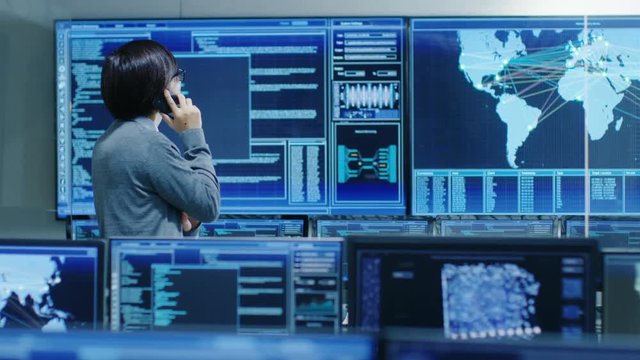 In the System Control Room IT Administrator Talks on the Phone. He's in a High-Tech Facility That Works on the Surveillance, Neural Networks, Data Mining, AI Projects.