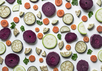 Fresh vegetables or vegetable background. Sliced slices of eggplant, beets, carrots, zucchini and parsley leaves on a white background. Sample of food. Delicious texture. View from above.