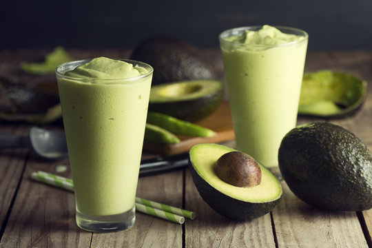 Two Glasses of Avocado Shake or Smoothie with Ingredients on Wooden Table