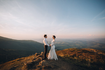 Blue sky spreads over wedding couple standing on the hill