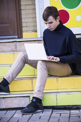 teen looks at a laptop outdoors in the city