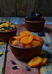 Composition from different varieties of dried fruits on wooden background - dates, apricots, prunes, raisins. Healthy food