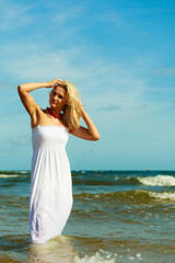 Blonde woman wearing dress walking in water