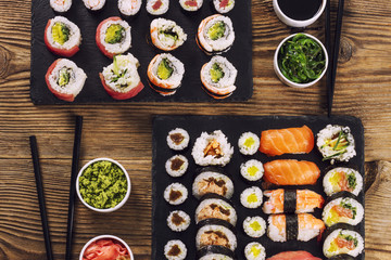 Sushi sets on a dark stone with chopsticks, wasabi and kelp