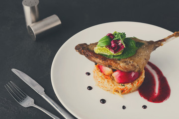 Restaurant meals. Duck confit with vegetables on black backgroun