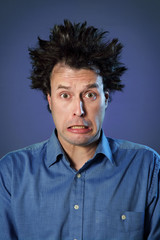 Fototapeta na wymiar Funny Portraits of a guy who has been electrified: hair standing up with different facial expression on blue background