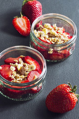 Homemade healthy dessert with strawberries and granola on a dark table