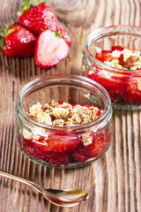 Two portions of strawberries with muesli on a wooden table