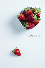 Strawberries in a white bowl on a white table with copyspace