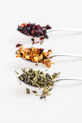 Various kinds on loose leaf tea on a metal spoons, side view