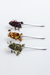 Different kinds of loose leaf tea on a metal spoons