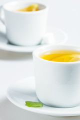 A cup of coffee with mint leaf on a saucer