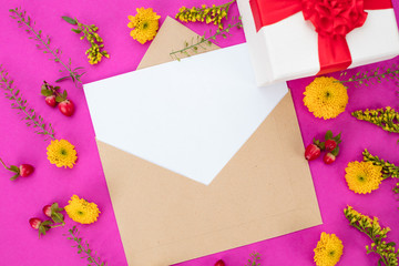 Romantic pink background of a blank card, a gift wrap with red bow and yellow flowers. Copy space, view from above