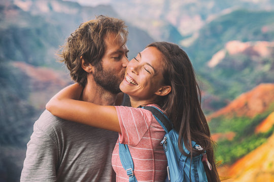 Couple in love kissing on nature travel hiking in mountains. Young hikers people happy together. Interracial backpacking lovers kiss portrait on vacation hike.