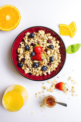 Strawberry, blueberry and orange muesli with honey on a white table