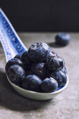 Fresh blueberries in blue ceramic spoon on a concrete table