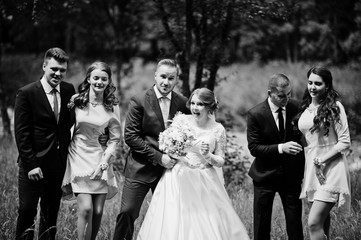 Crazy and happy newlyweds having fun with bridesmaids and groomsmen in the park.