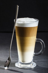 Ideal latte machiato coffee and spoon on a dark background