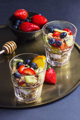 Granola desserts and bowl with fresh fruits on a golden tray
