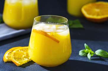 A glass of fresh orange juice with ice on a stone table